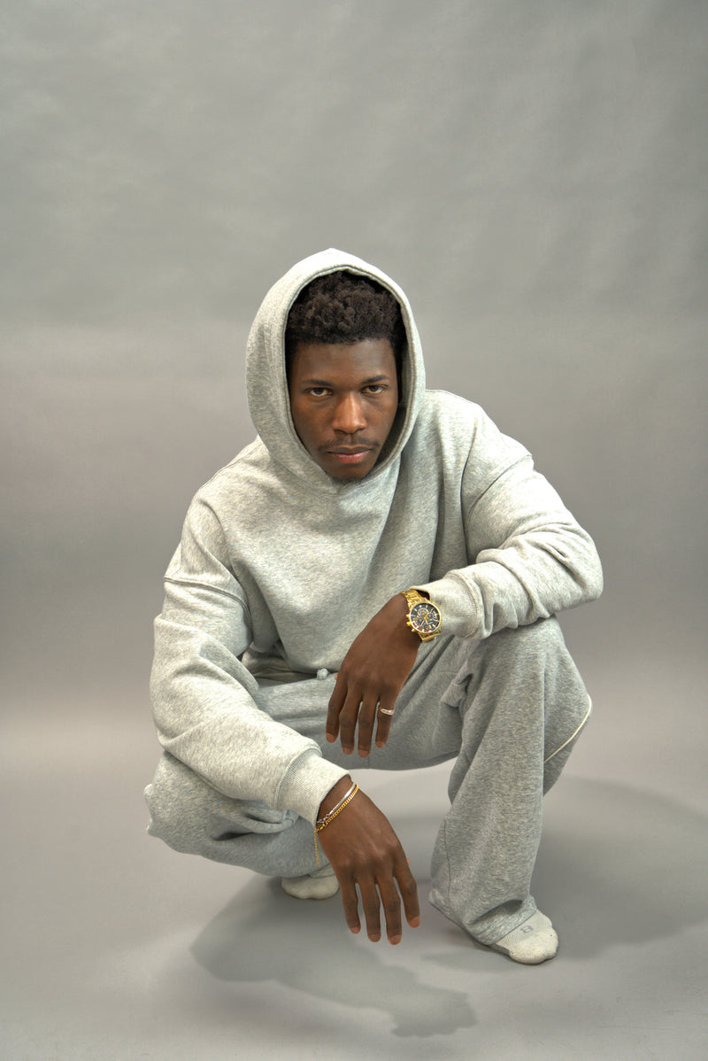 Man wearing a gray hoodie and pants on a gray background