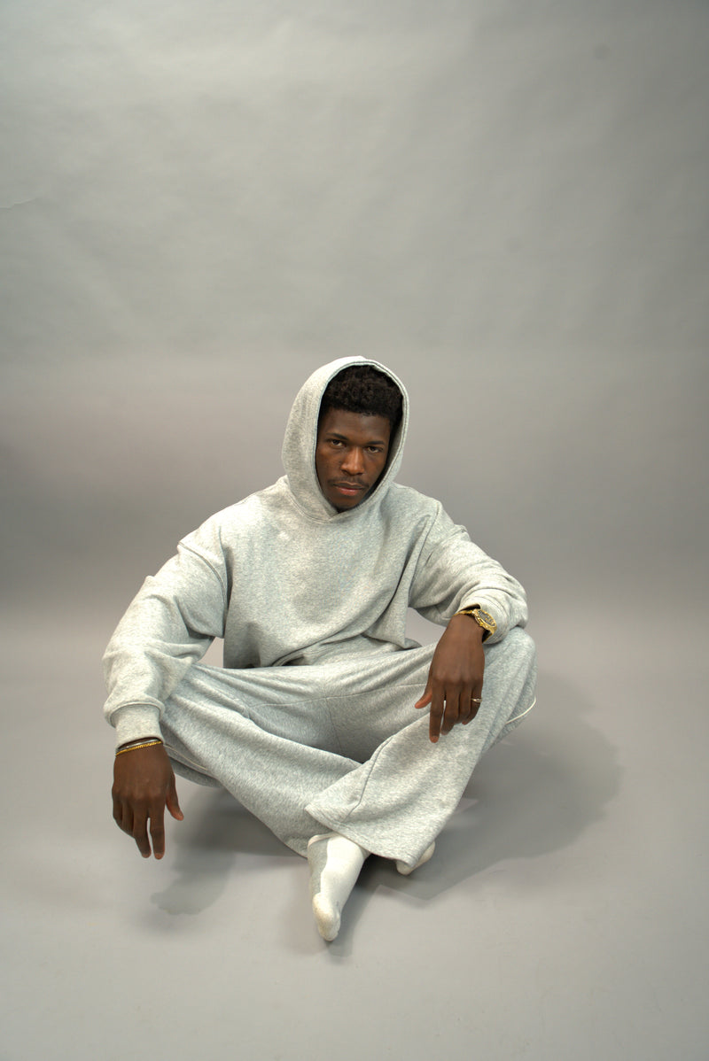 Person wearing a white hooded outfit sitting on a gray background